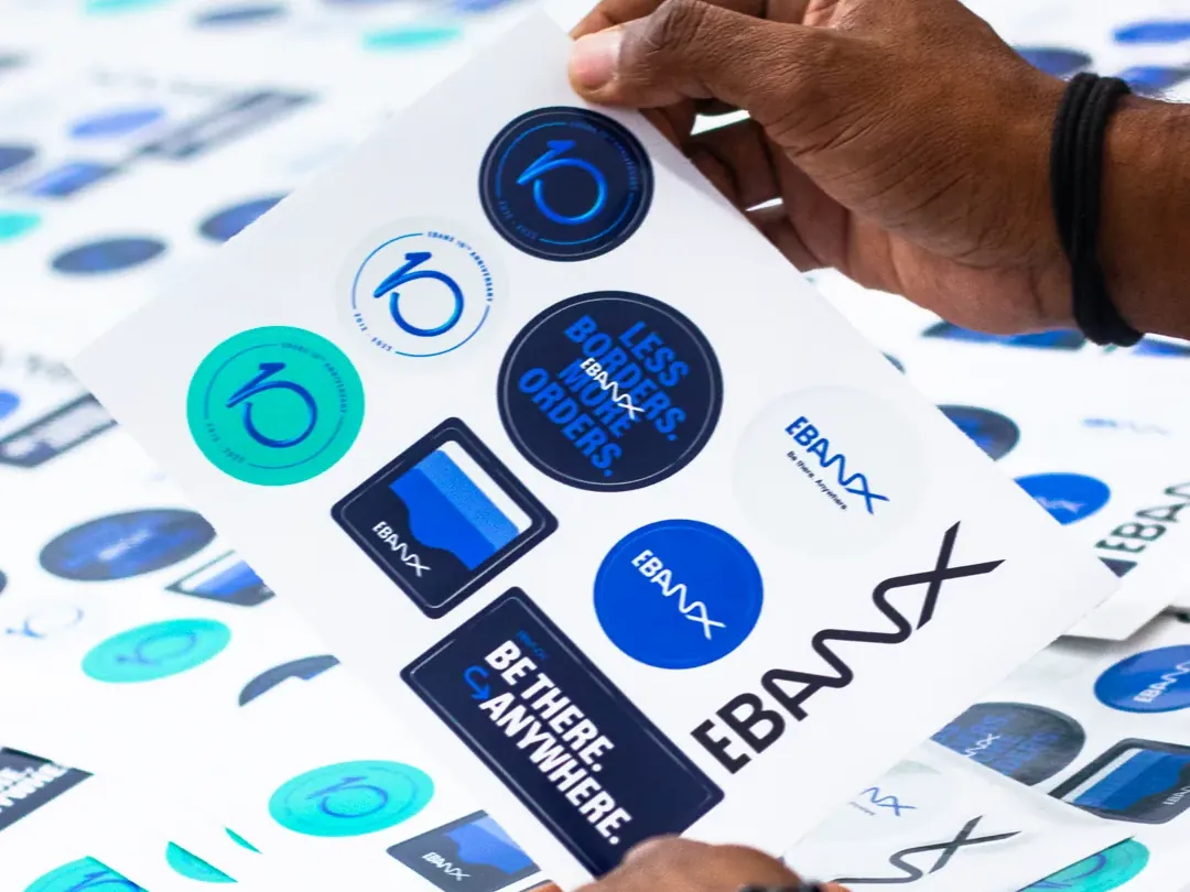 Mãos segurando uma cartela de adesivos personalizados com a marca de uma empresa
