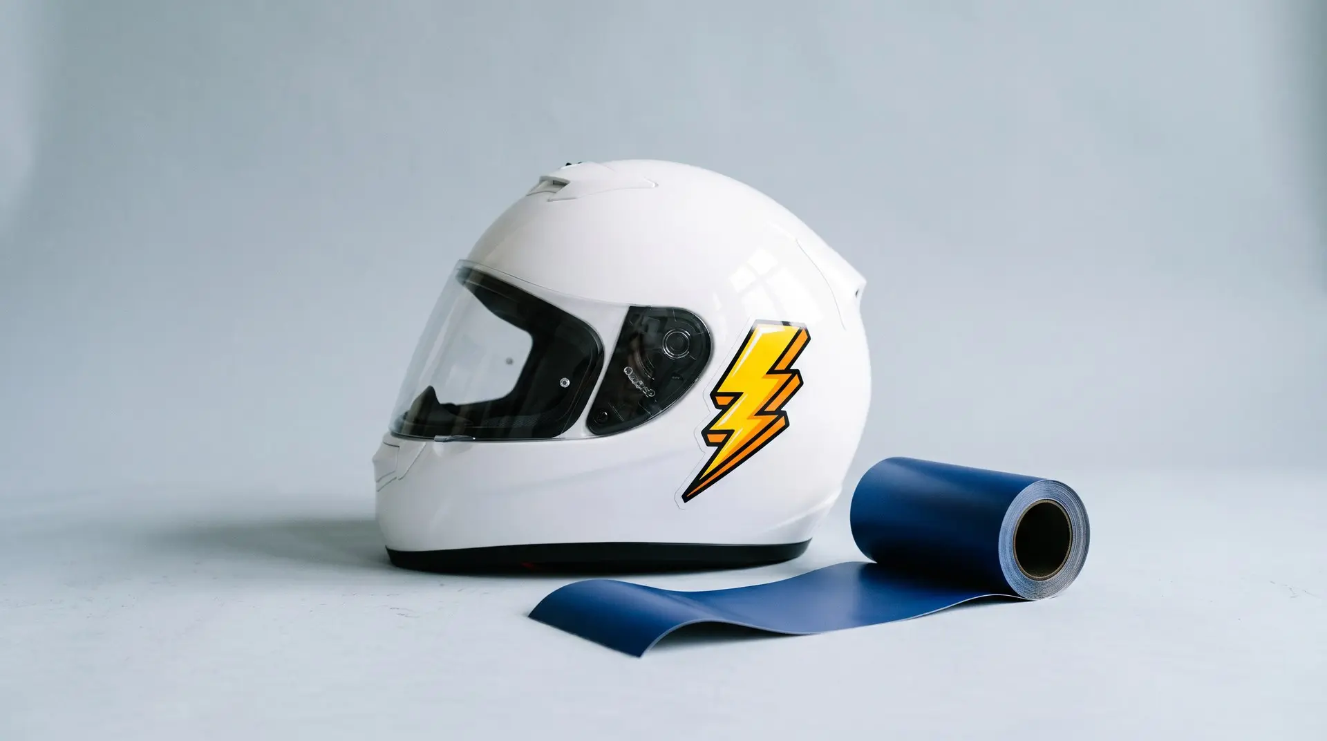 Capacete branco com adesivo de vinil premium ao lado de rolo de vinil para envelopamento