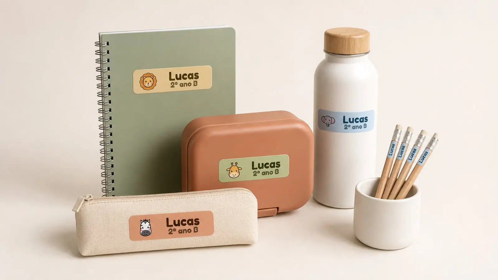 Caderno, lancheira, garrafinha, estojo e lápis com etiquetas de safári com o nome Lucas